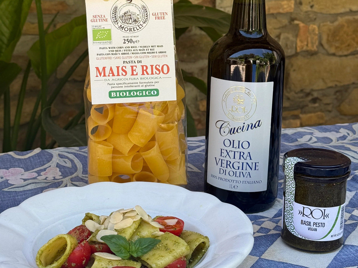 Gluten-free Morelli paccheri pasta tossed in creamy green ROI vegan pesto, garnished with cherry tomatoes, toasted almonds, and fresh basil.