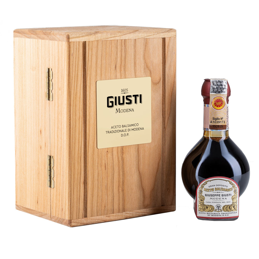 Bottle of Giusti aceto balsamico with wooden box on a white background