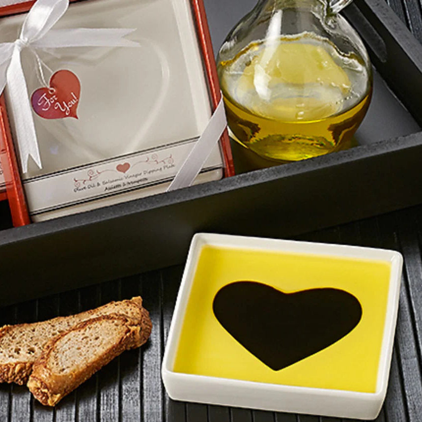 Gift set with olive oil, bread, and a heart-shaped container on a wooden surface.