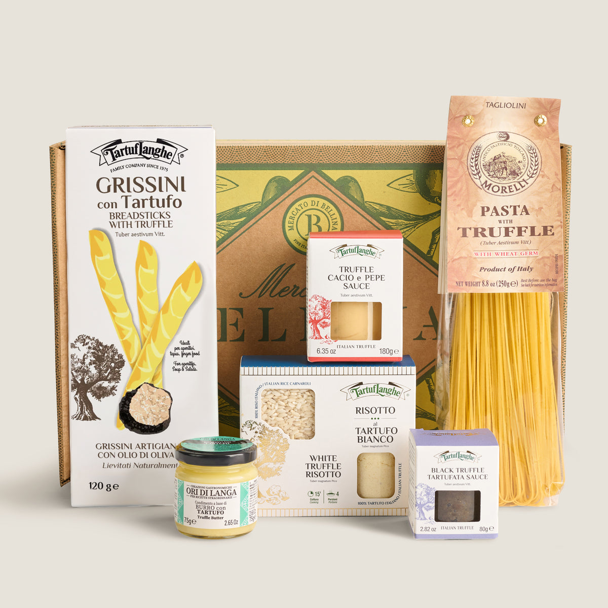 A curated gourmet gift set from Mercato di Bellina featuring truffle products, pasta, and sauces arranged in front of a decorative gift box on a light beige background. The set includes Grissini con Tartufo, Pasta Truffe, Truffe Cacio e Pepe , Risotto, White Truffe Butter, Black Truffe sauce.