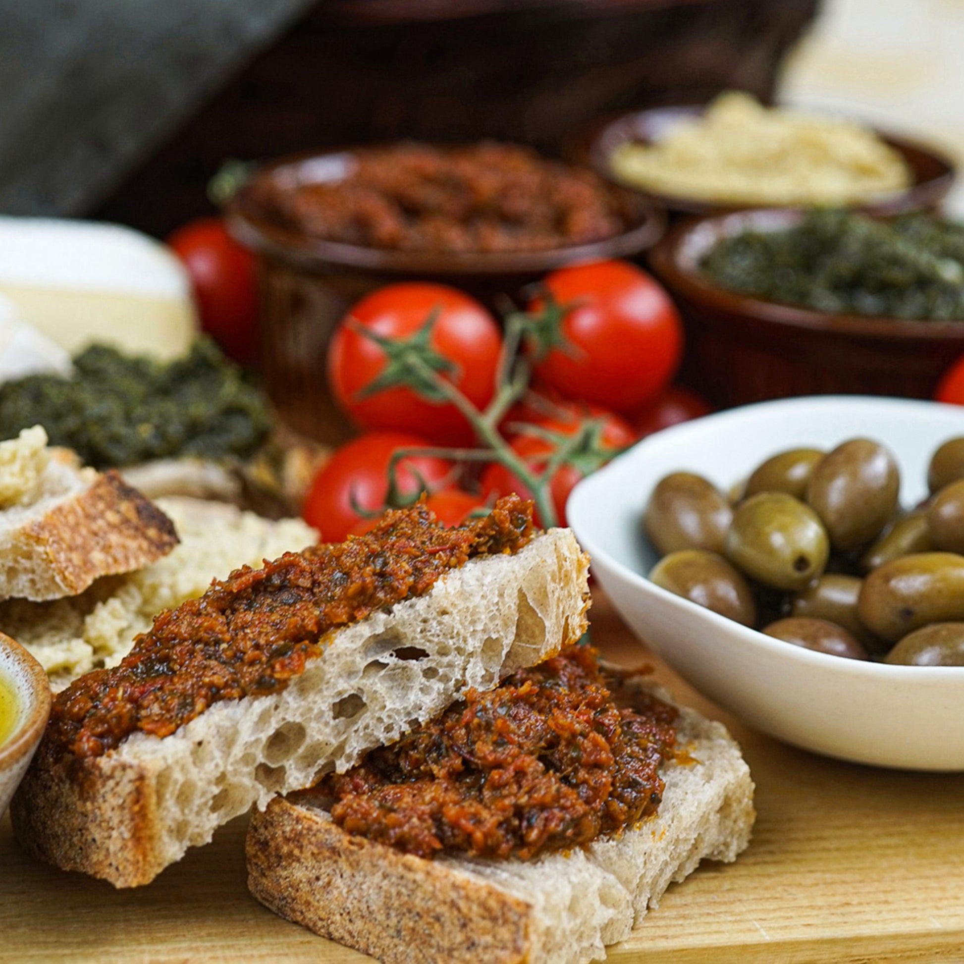 Slices of rustic bread topped with Italian tomato spread, olives, and tomatoes