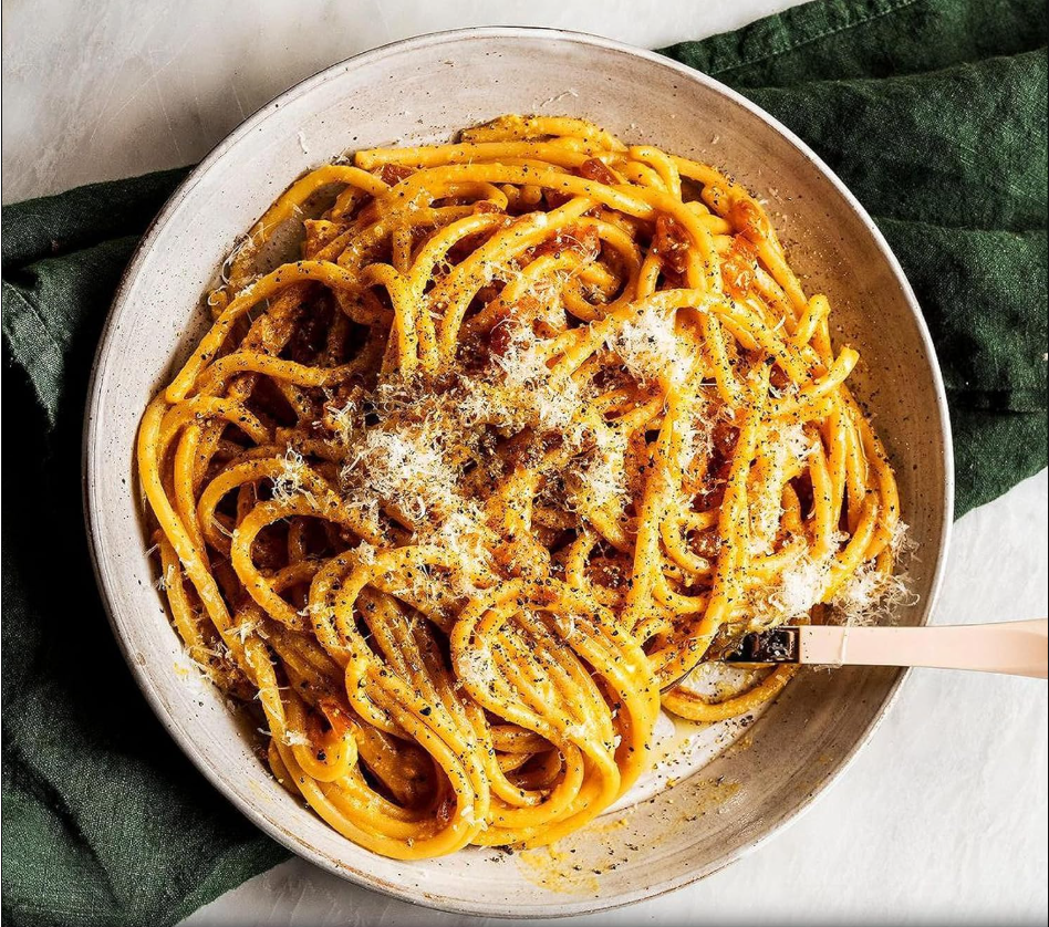 Plate of bucatini carbonara with grated cheese and black pepper