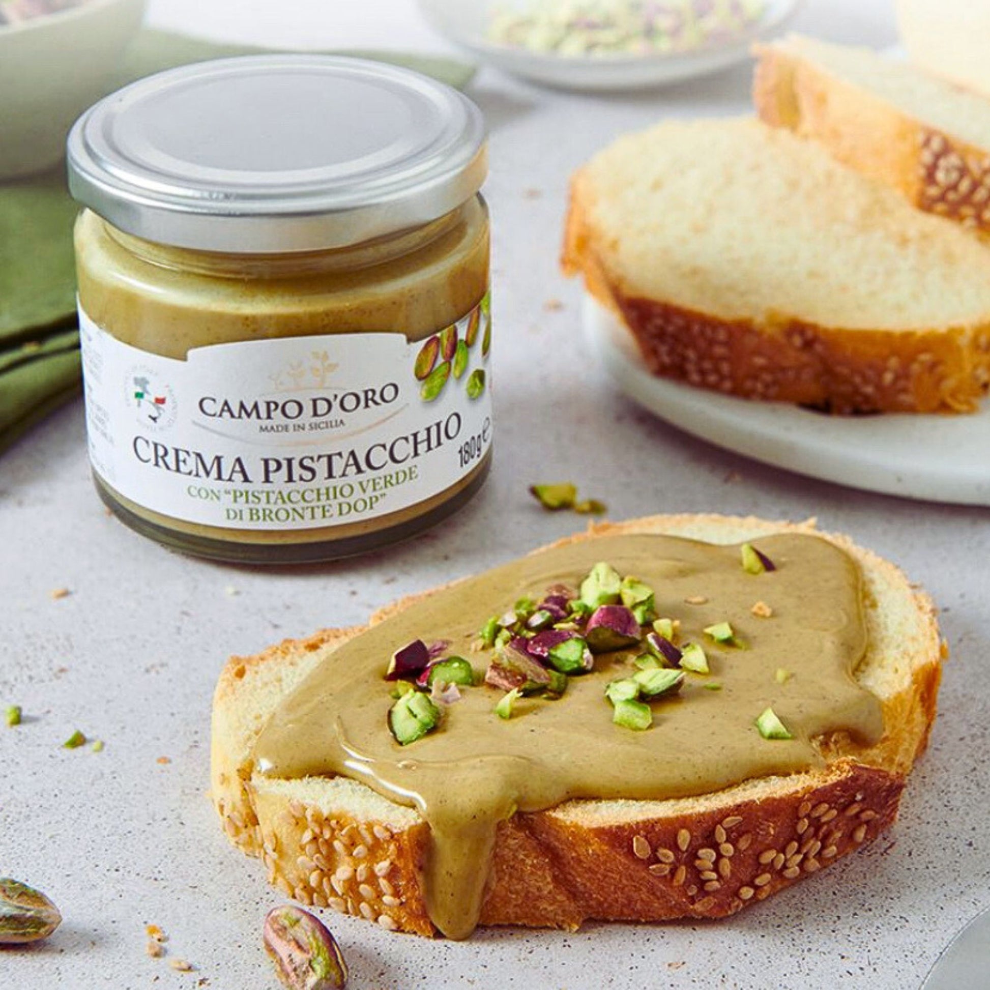 Jar of Campo d’Oro pistachio butter spread on bread with chopped pistachios