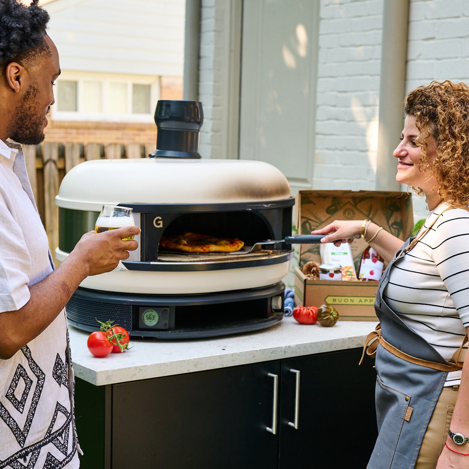 Woman baking homemade pizza in outdoor oven with Italian toppings