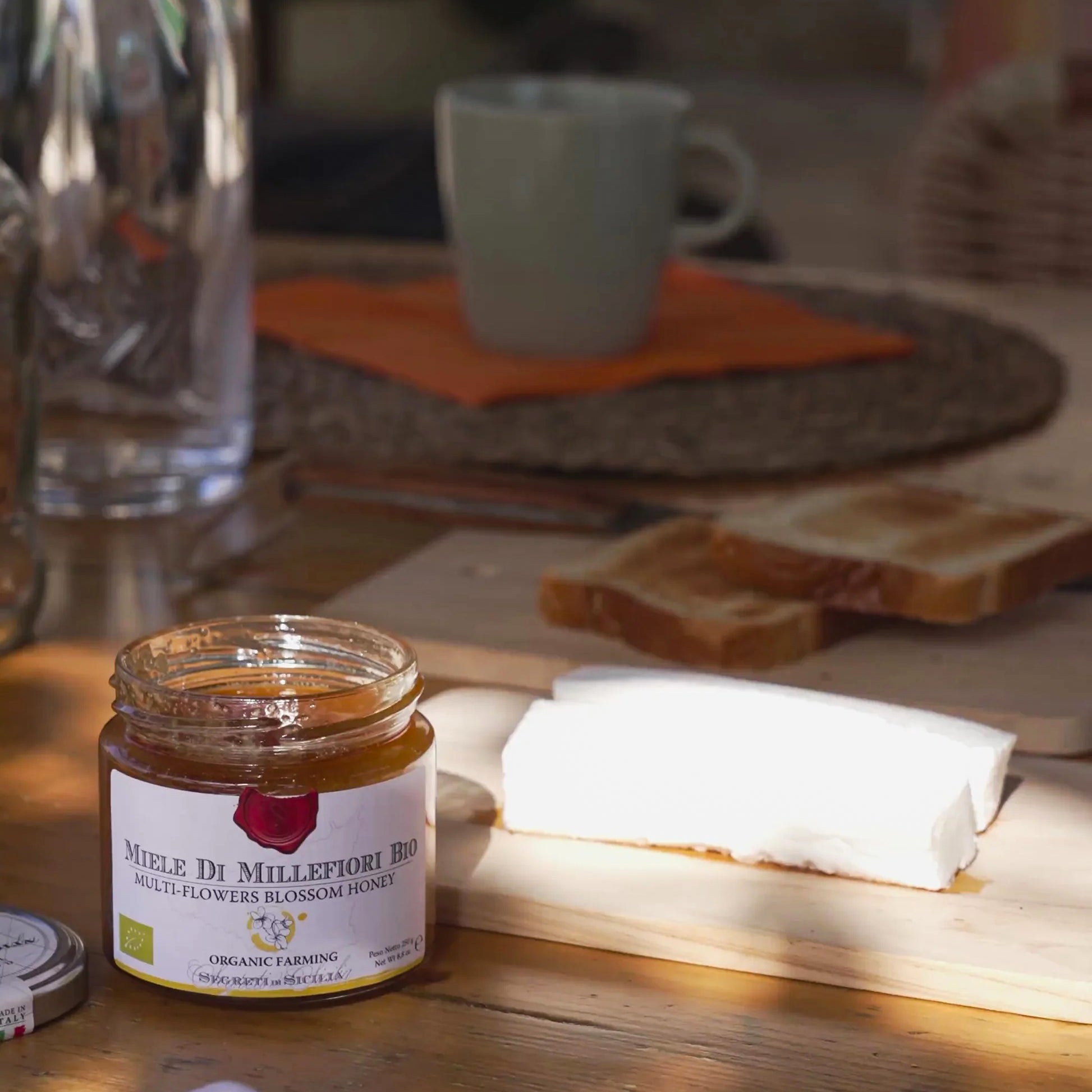 Jar of organic multi-flower honey with bread and coffee on rustic table