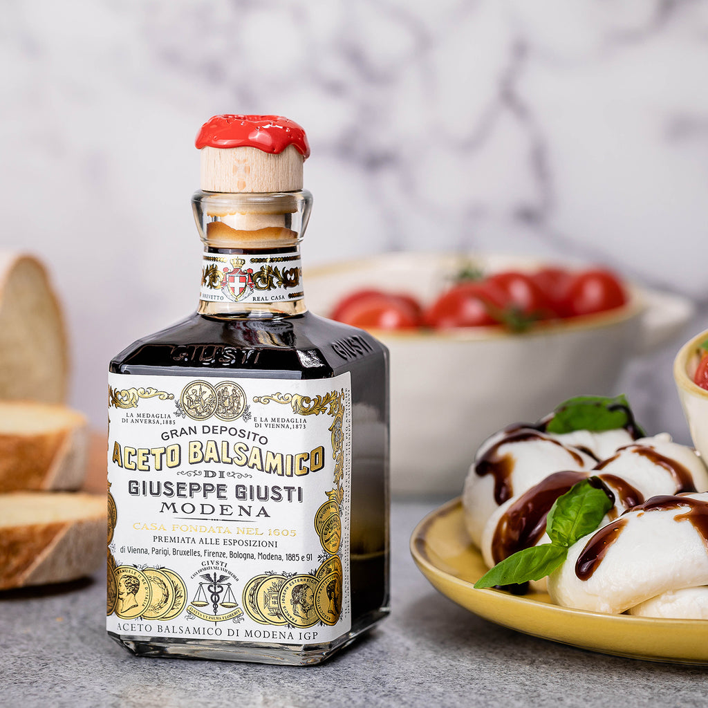 Bottle of Giuseppe Giusti balsamic vinegar next to mozzarella, basil, and tomatoes