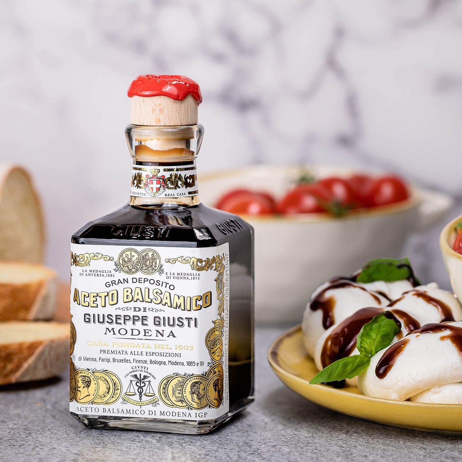 Bottle of Giuseppe Giusti balsamic vinegar next to mozzarella, basil, and tomatoes