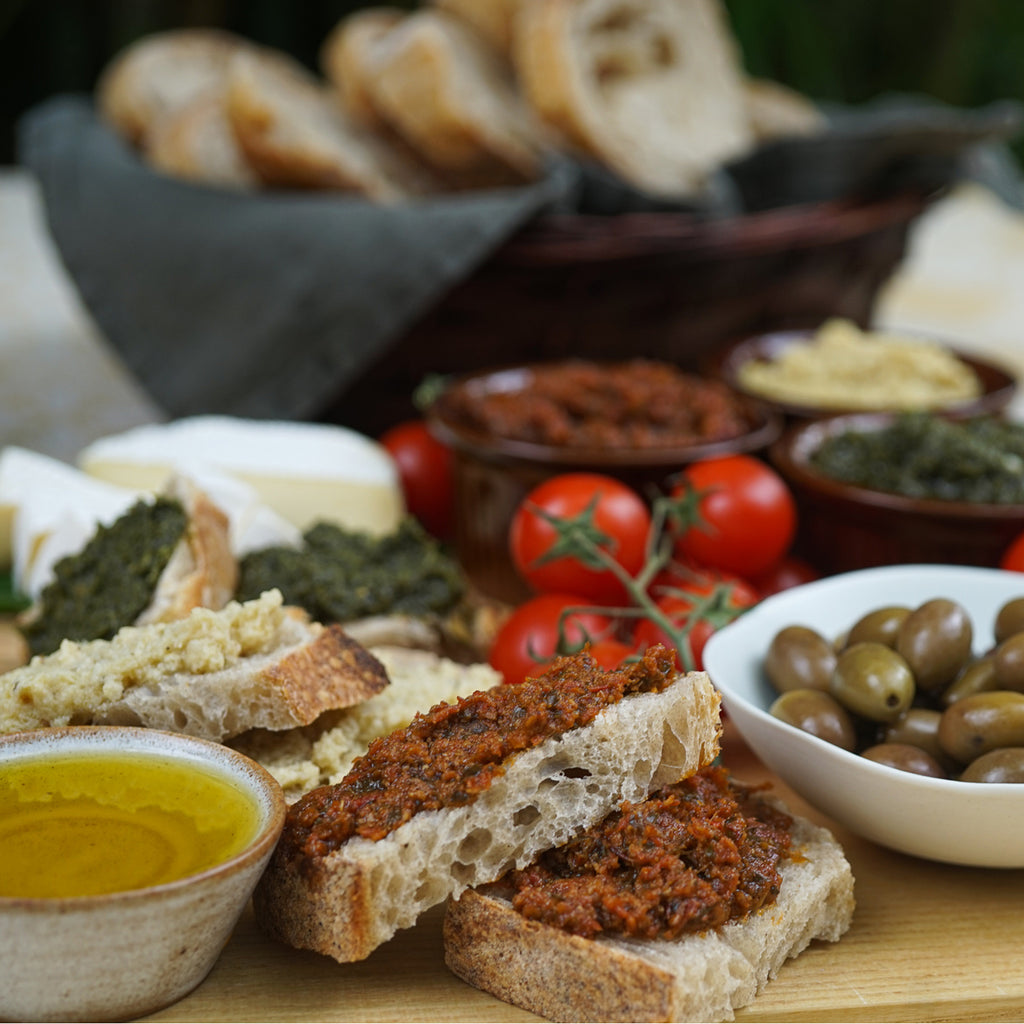Aperitivo board with olives, bruschetta spreads, tomatoes, and fresh bread