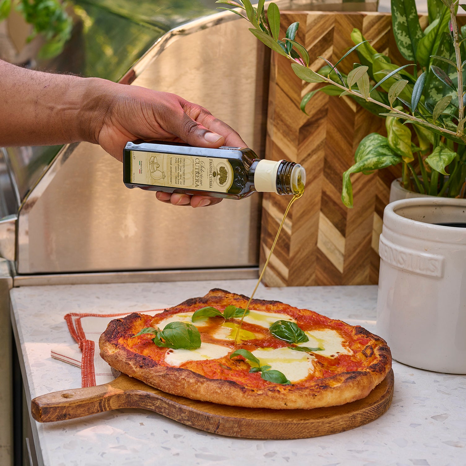 Homemade pizza topped with mozzarella, tomato sauce, basil, and olive oil drizzle