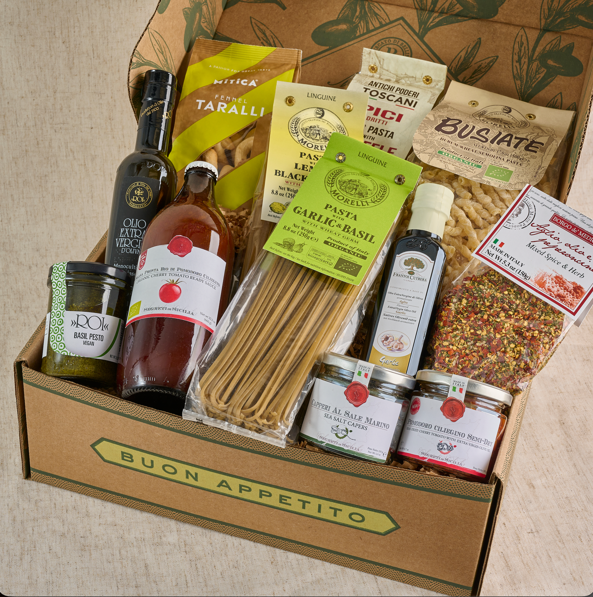 Gourmet food box with pasta, sauces, and other Italian products on a neutral background