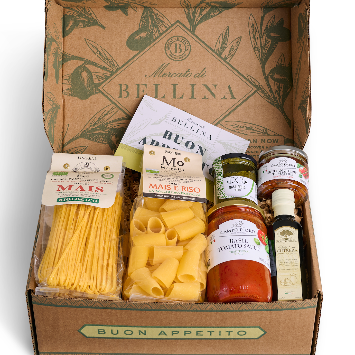 An open cardboard gift box labeled 'Buon Appetito' and 'Merco di Bellina' filled with Italian pasta ingredients, including tubes of pasta, jars of tomato sauce, olive oil, and a bag of dried spaghetti.