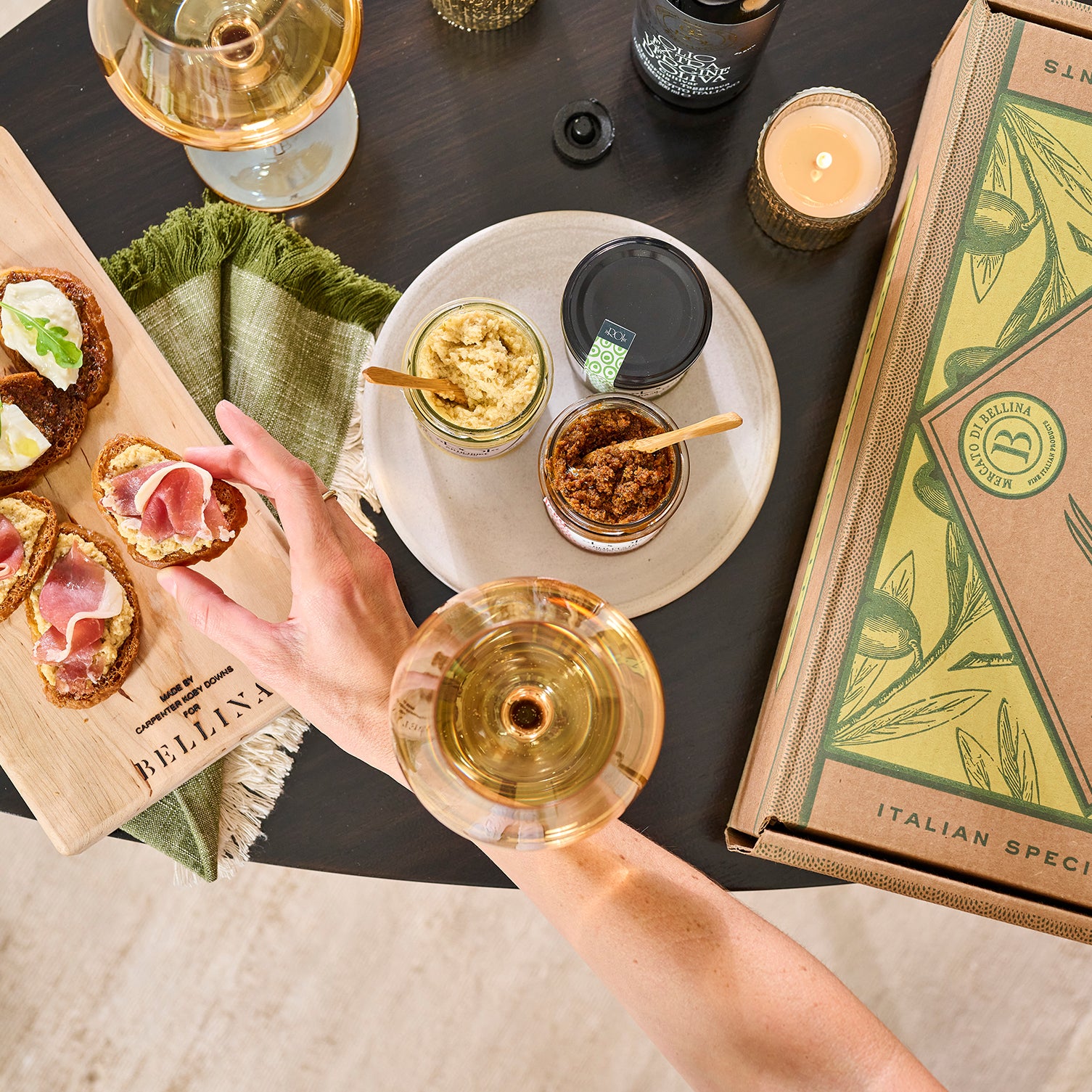 Glasses of wine with crostini, spreads, and Bellina gift box on dining table