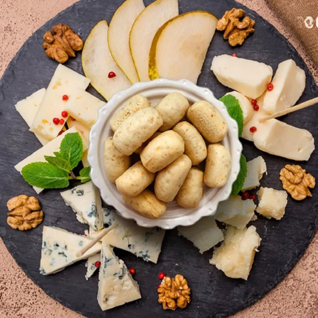 Mini grissini breadsticks served with assorted cheese, walnuts, pears, and mint