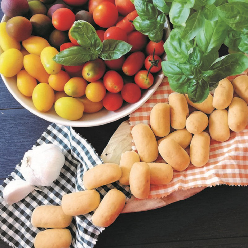 Mini grissini breadsticks with cherry tomatoes, basil leaves, and garlic on table